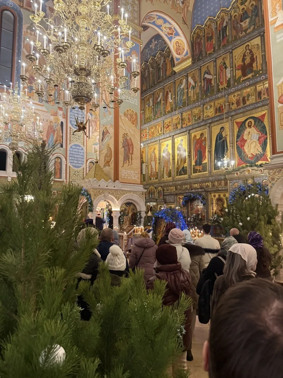 L'intérieur d'une église russe pendant l'office de Noël, sapins et iconostase