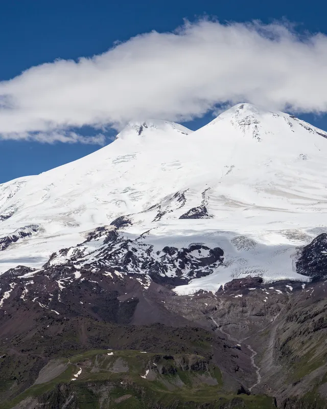 Les deux sommets enneigés de l'Elbrouz sous un nuage, vus depuis le Tcheget