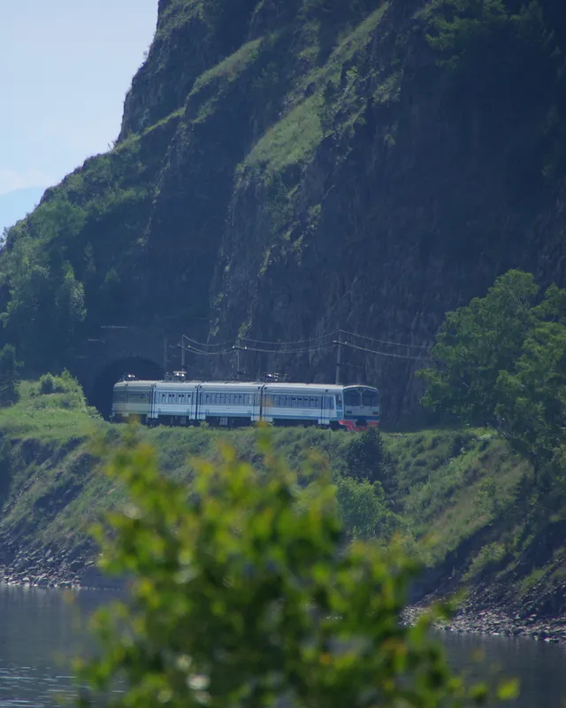 Un train longe une falaise boisée au bord du lac Baïkal, sur le Circum-Baïkal